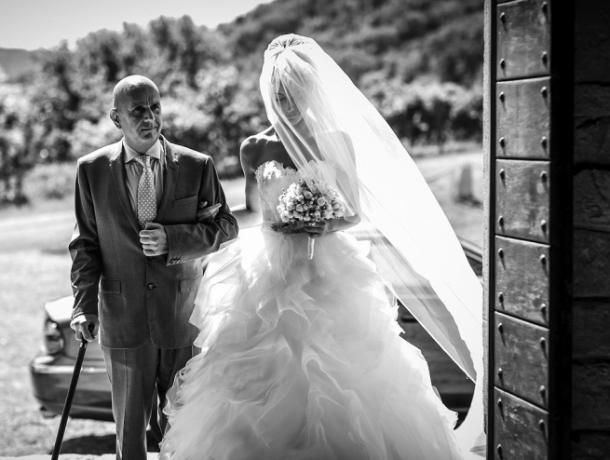 The bride enters an old country church with her father during a wedding in Italy. © Cristiano Ostinelli The bride with her father at wedding in Italy